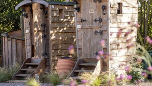 A rustic wooden outhouse with a sign indicating a toilet, a lantern, and a nameplate. - Luxury Tent-Peaceful Meadow-Firepit-Superb Views.Dogs WiFi-Beaches 10 mins SAUNA (Truro)