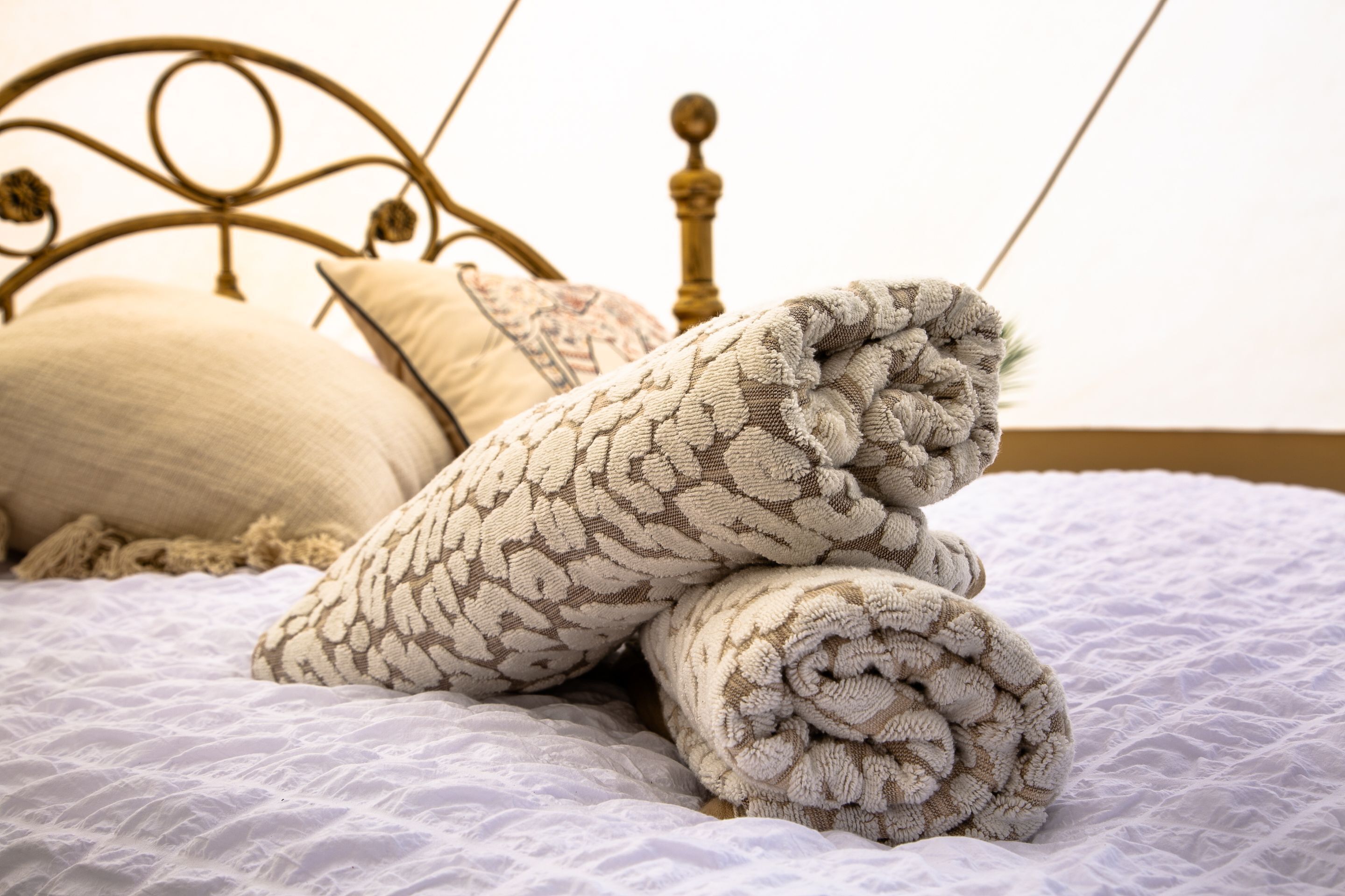 Un lit avec une couverture et des oreillers à motifs, une tête de lit en métal et un mur uni.