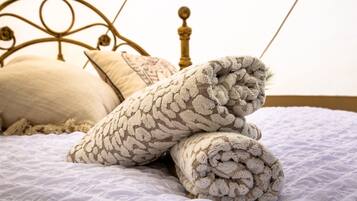 Un lit avec une couverture et des oreillers à motifs, une tête de lit en métal et un mur uni.