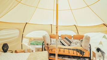 Una tenda con un letto, cuscini, un tavolino e un oggetto decorativo.