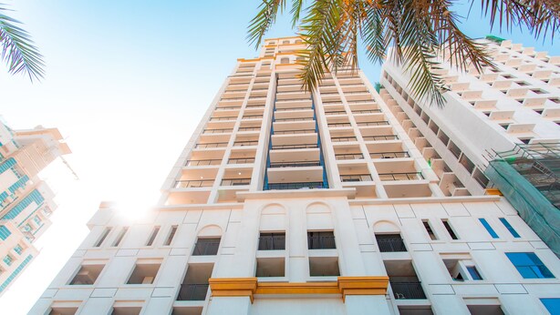 A tall, modern building with multiple balconies and a central entrance.