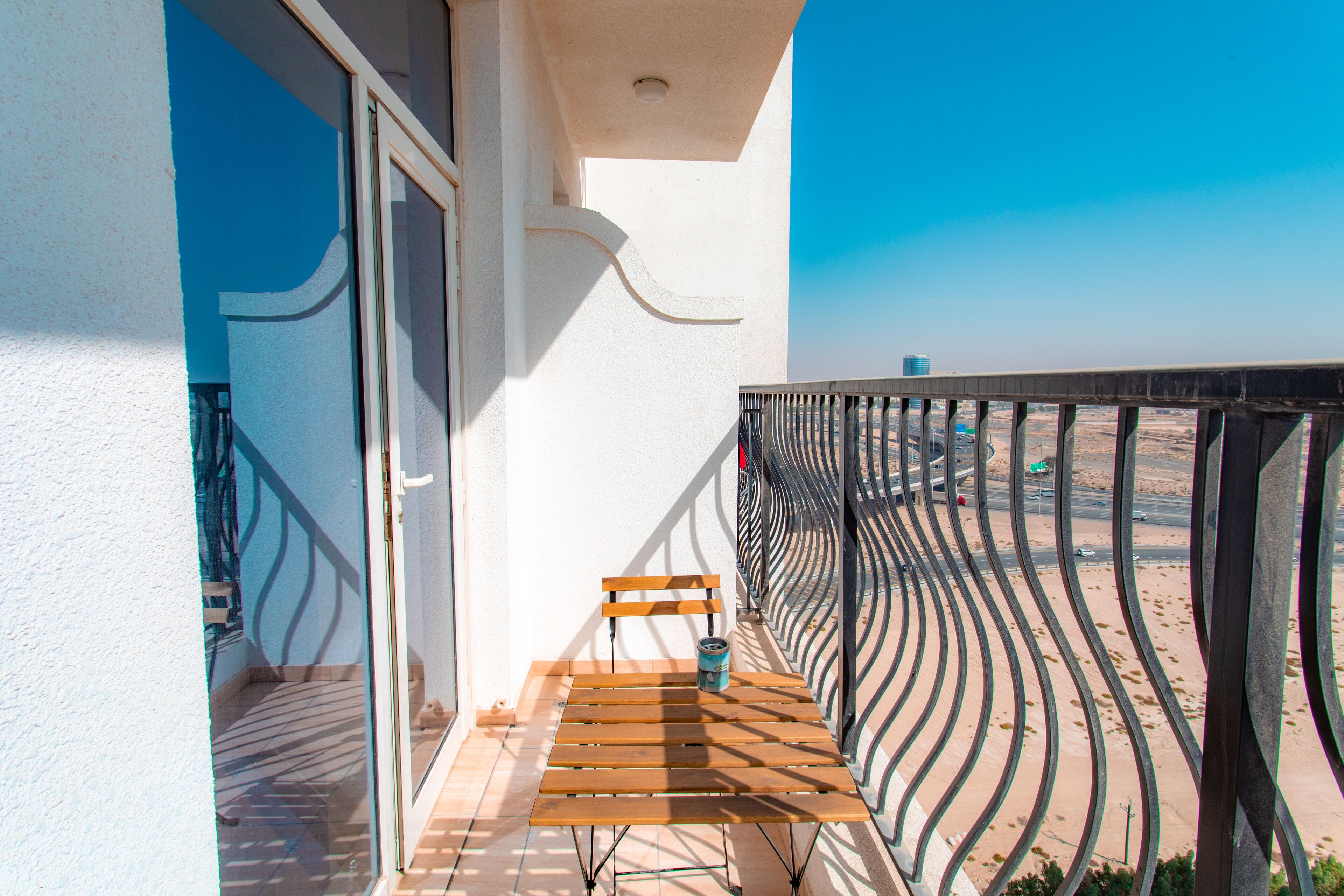 A balcony with a wooden bench and a can of drink, overlooking a desert landscape.
