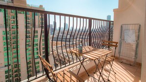 A balcony with a view of a cityscape, a metal rack, and a wooden table.