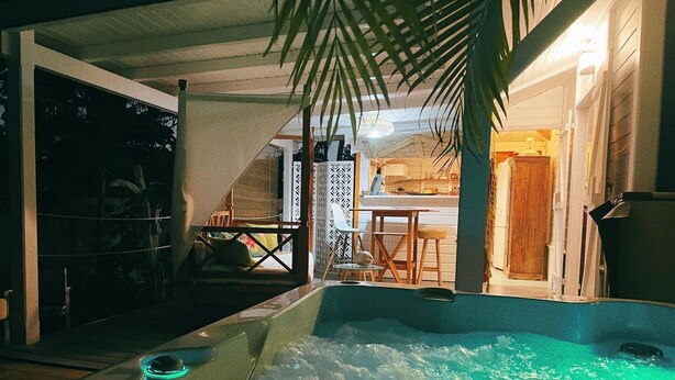 A hot tub area with a wooden deck, a small table, and a chair. - Charming bungalow for 2 with private Jacuzzi (Saint-François)