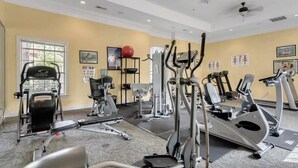 Un gimnasio con varios equipos de ejercicio, incluyendo cintas de correr, elípticas y una bicicleta estática.