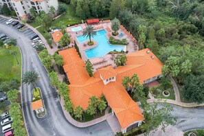 Vista aérea de un hotel con piscina, palmeras y aparcamiento.