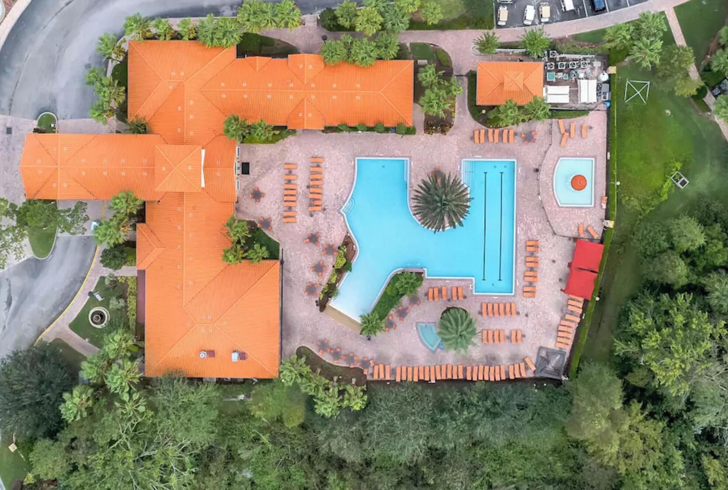 Eine Vogelperspektive zeigt ein Resort mit mehreren Schwimmbecken, darunter ein großes zentrales Becken, umgeben von Liegebereichen.