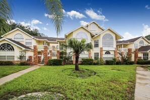 Stately building with a central entrance and two wings, surrounded by manicured lawns and a palm tree.