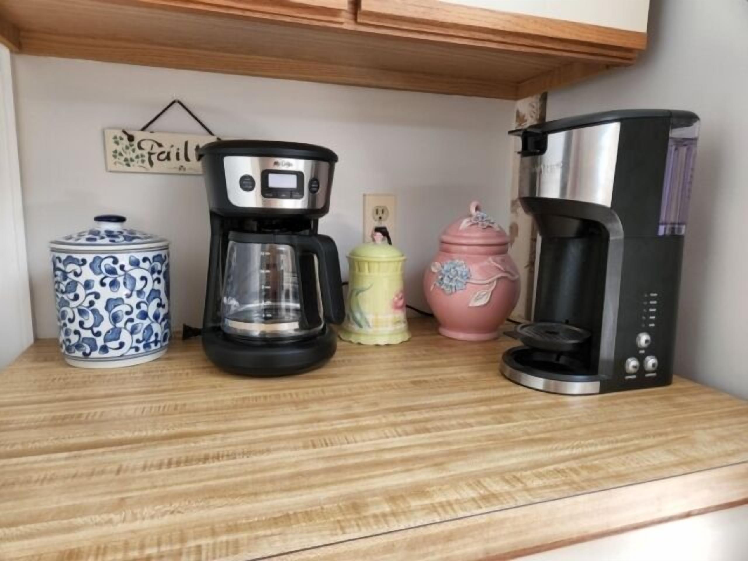 A kitchen counter with a coffee maker, a decorative jar, and a ceramic container.