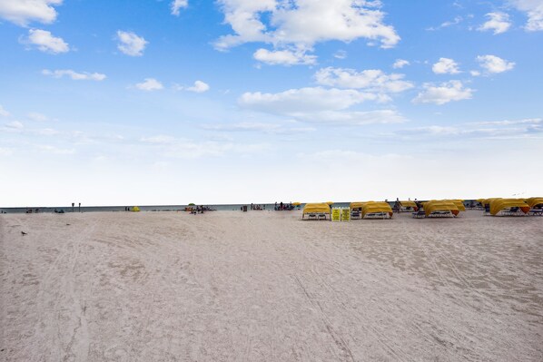 Una playa con sombrillas amarillas y una orilla arenosa.