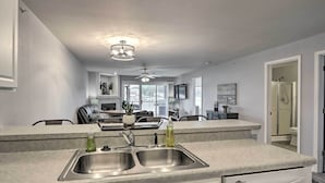 A modern kitchen with a double sink, a ceiling fan, and a view to the dining area. - Poolside Fun! Lake-View Camdenton Condo (Camdenton)