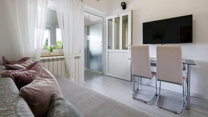 A modern hotel room with a bed, a desk with two chairs, a flat-screen TV, and a door leading to a bathroom. - Apartment SoMi 2 (Poreč)