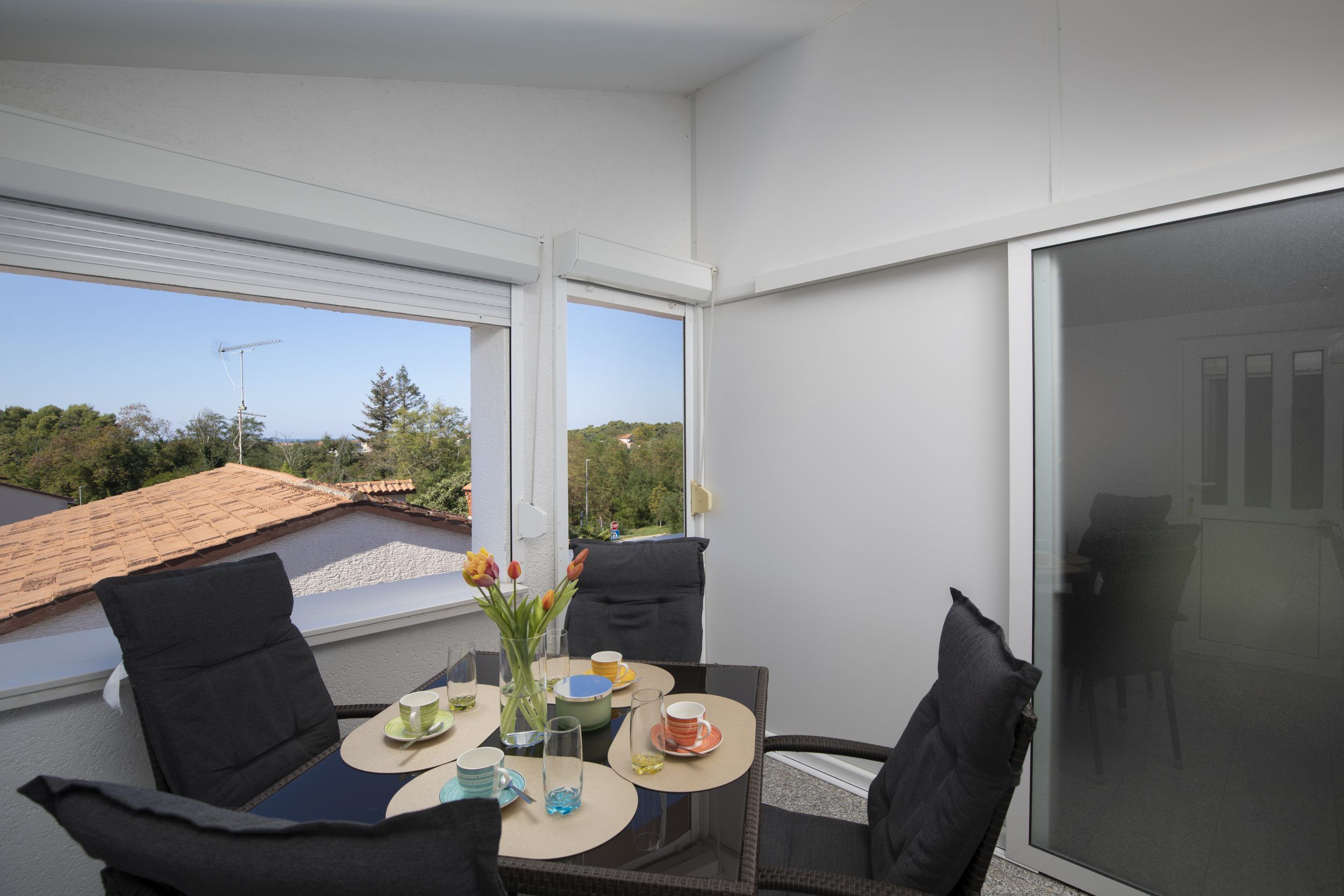 Ein Balkon mit einem Tisch für zwei Personen, Stühlen und Blick auf die Umgebung.