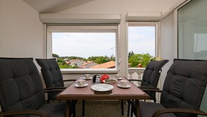 A balcony with a table set for four, chairs, and a view of a town. - Apartment SoMi 2 (Poreč)