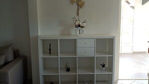 Une étagère blanche agrémentée d’objets décoratifs et d’un vase avec des fleurs.