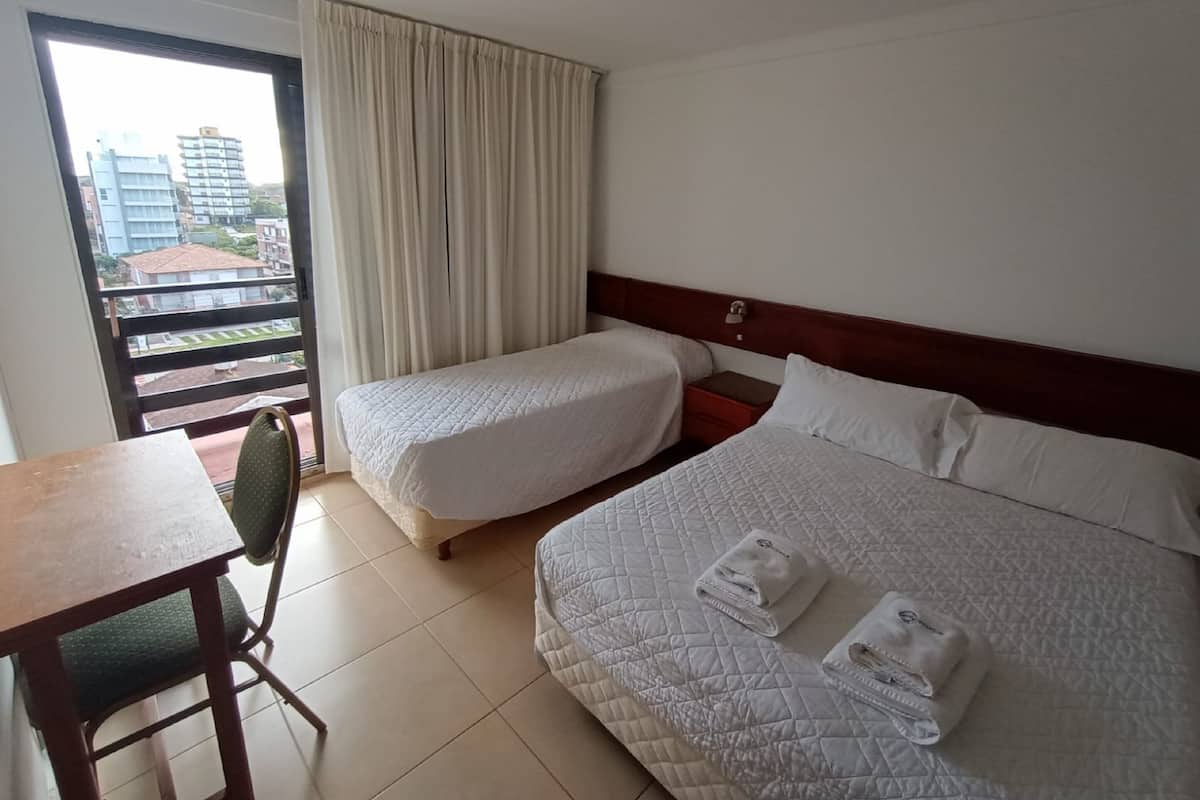 A hotel room with two beds, a desk, and a chair.
