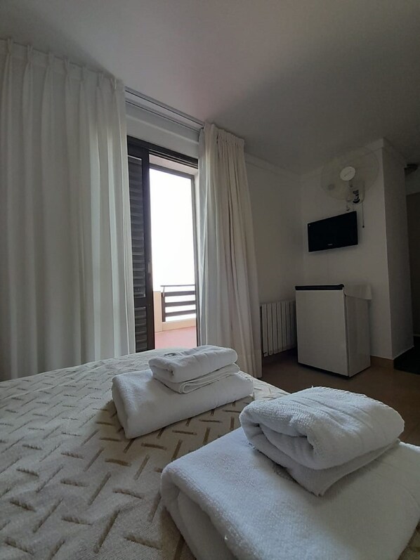 A hotel room with a bed, a radiator, a TV, and a balcony. - Intersur Villa Gesell (Villa Gesell)