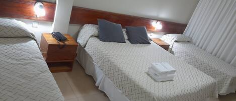 A hotel room with two beds, each with a wooden headboard, white bedding, and a nightstand with a telephone.