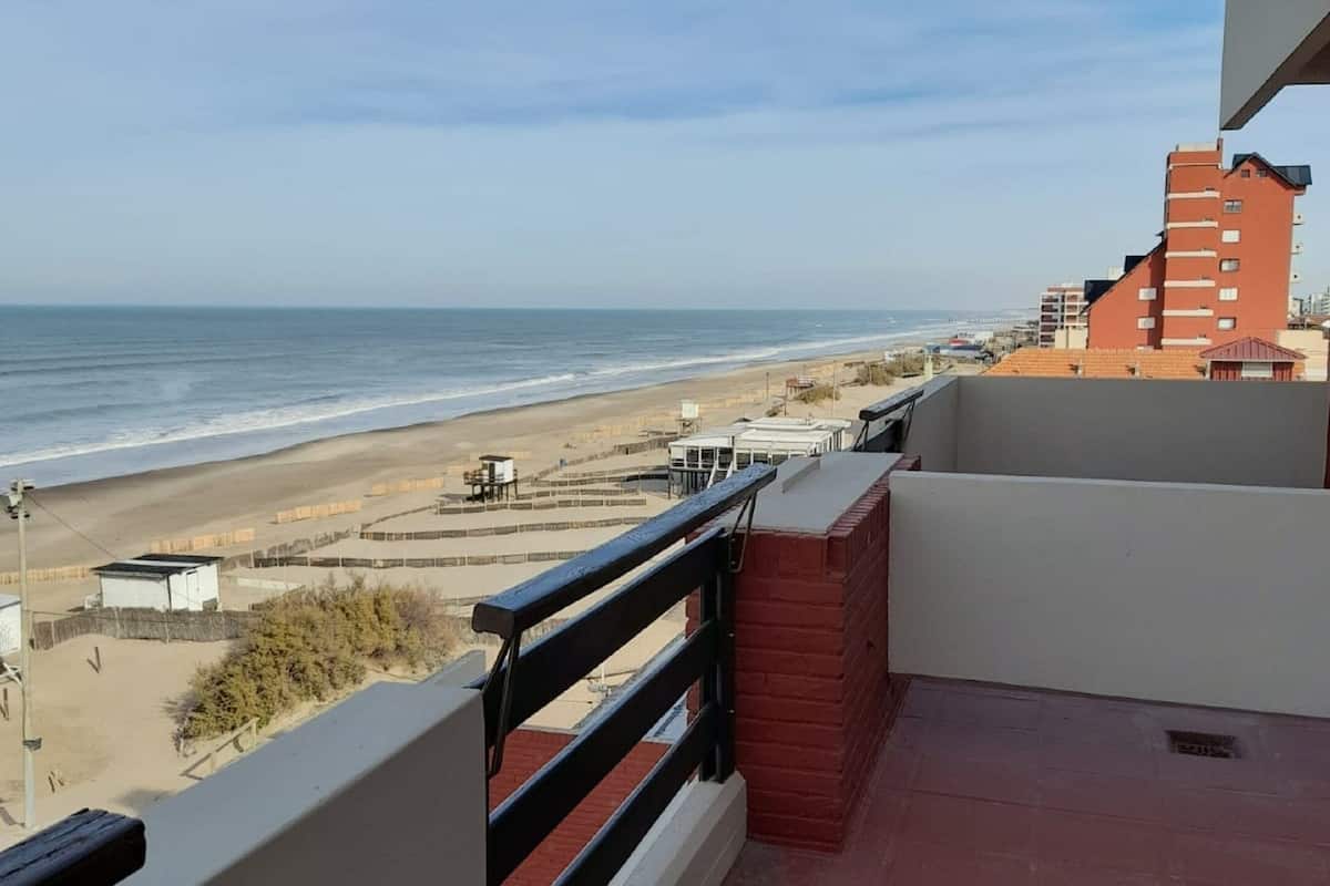 A balcony with a view of the beach and ocean.