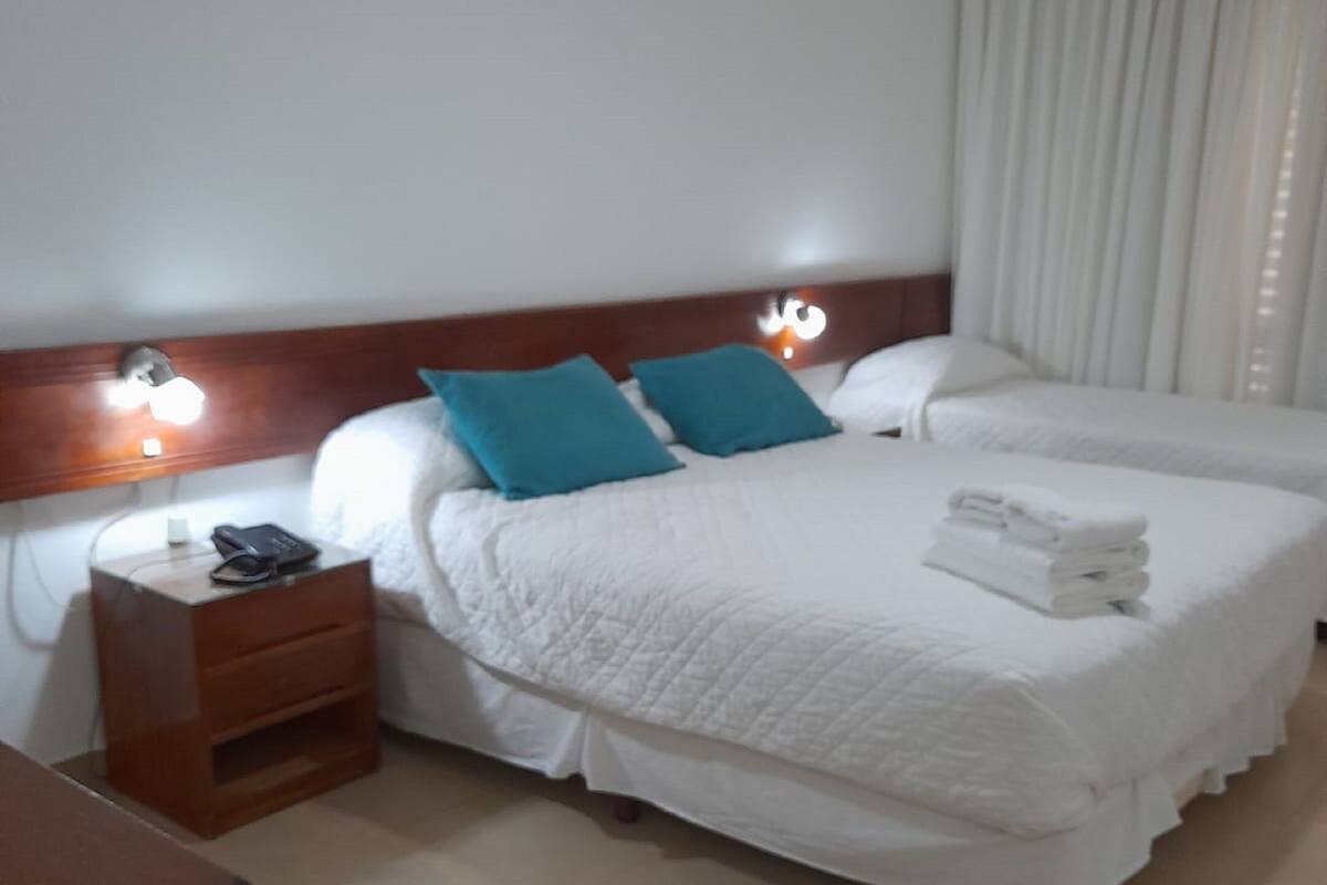 A hotel room with a large bed, two bedside tables, and a nightstand.