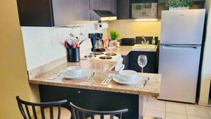 Une cuisine avec coin repas, équipée d’un réfrigérateur, d’un four à micro-ondes et d’une machine à café.