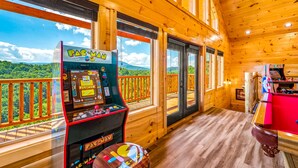 A wooden cabin with a pool table and arcade games, featuring large windows with a view of a forested mountain range. - Free Attractions | Indoor Heated Pool, Game Room, Fireplace, Views (Sevierville)