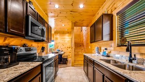 A modern kitchen with wooden walls, granite countertops, stainless steel appliances, and a built-in oven. - Free Attractions | Indoor Heated Pool, Game Room, Fireplace, Views (Sevierville)