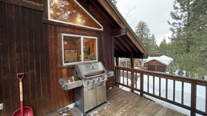 Eine Holzterrasse mit Grill und einer roten Schaufel.