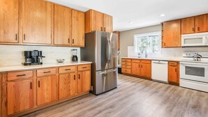 Une cuisine moderne avec des meubles en bois, des appareils électroménagers en acier inoxydable et un plan de travail blanc.