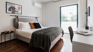 A modern hotel room with a bed, a desk, and a view of the outdoors. - Top-Class 2BR Apartment in Marousi (Marousi)