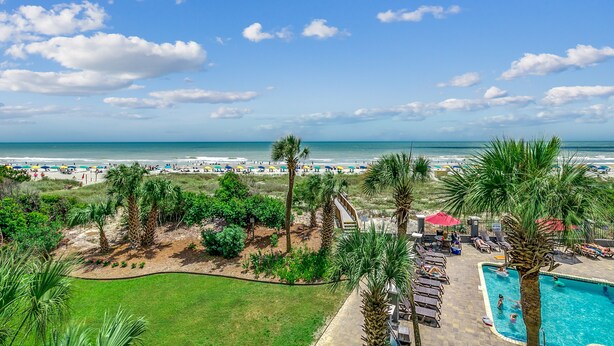 A resort with a pool, palm trees, and a view of the beach and ocean. - 🌟Oceanfront | Awesome Amenities | Great Views | Carolina Dunes 204🌟 (Myrtle Beach)