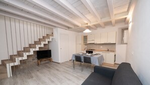 A modern living room with a staircase, a dining area, and a kitchen.
