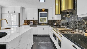 A modern kitchen with white cabinetry, a black and gold backsplash, and a central island.