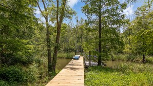 A wooden dock extending into a forested area with a body of water.