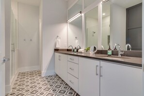 Une salle de bain moderne avec un grand miroir, une douche et un meuble-lavabo.