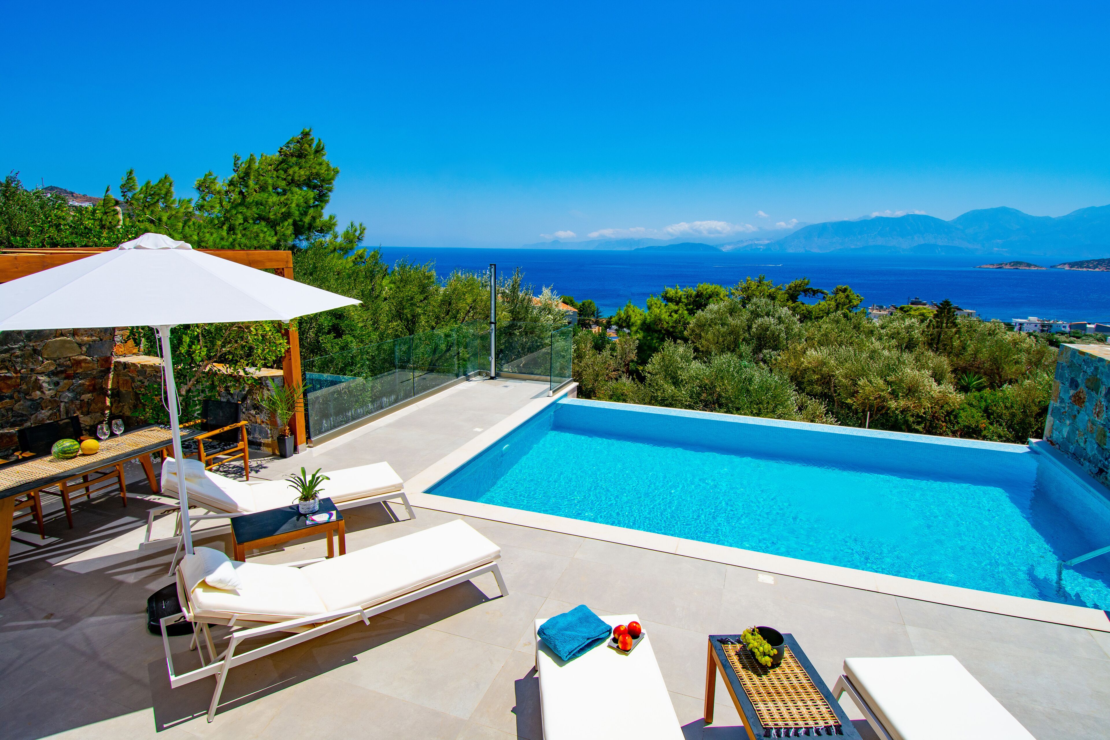 A poolside area with lounge chairs, a table, and a pergola.