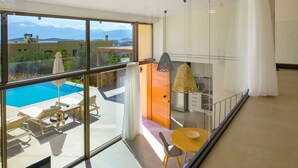 Un salon moderne avec un mur de verre donnant sur une piscine et des montagnes.