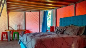 A bedroom with a bed, a desk, and two stools. - Green Willow (Cañon City)