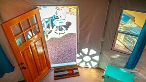 A room with a wooden door, a welcome mat, a window, and a turquoise storage box. - Green Willow (Cañon City)