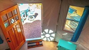 A tent with a wooden door, a welcome mat, and a turquoise toolbox.