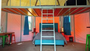 A tent with a bunk bed, a ladder, a table, and chairs.