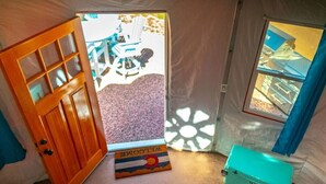 A room with a wooden door, a window, and a blue suitcase. - Orange Sunset (Cañon City)