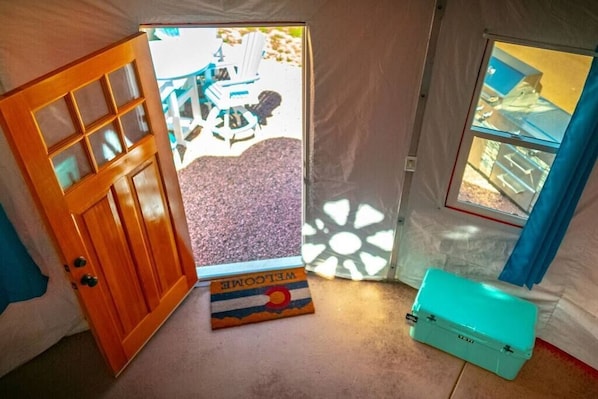 A room with a wooden door, a window, and a blue suitcase.