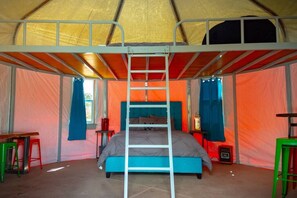 Une tente équipée d’un lit superposé, d’une échelle et d’une petite table avec une chaise.