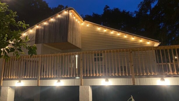Un edificio in legno con un balcone, luci a stringa e una recinzione.