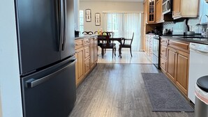 Una cucina moderna con frigorifero nero, mobili in legno e zona pranzo con tavolo e sedie.