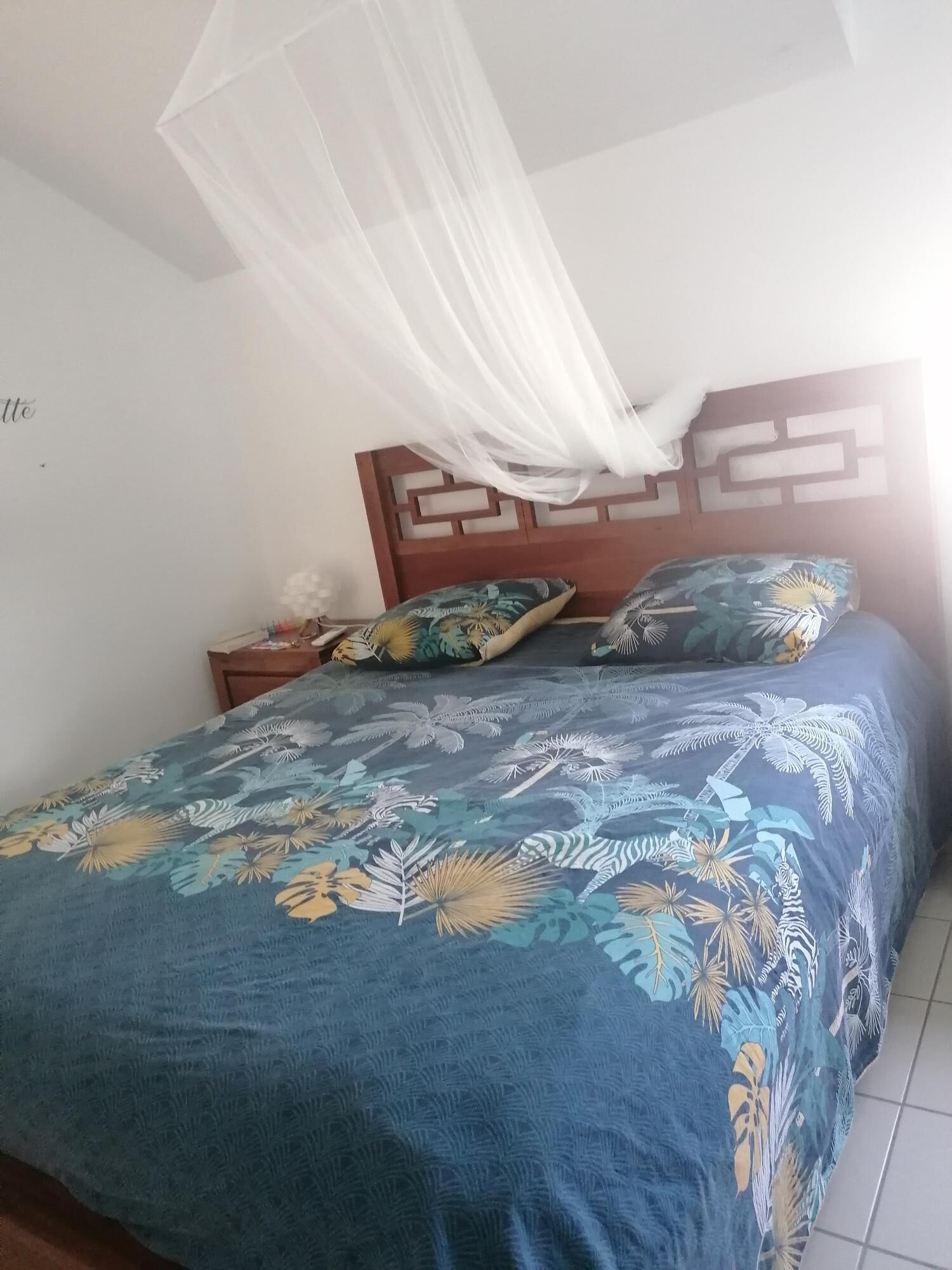 A bed with a floral bedspread, a wooden headboard, and a nightstand with a lamp.