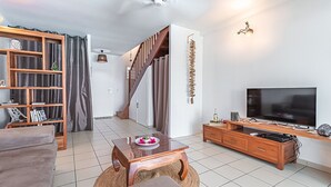 A modern living room with a sofa, a wooden coffee table, a TV stand, and a staircase. - Ô Rêves Bleus - Two Bedroom Apartment, Sleeps 4 (Saint-Francois)