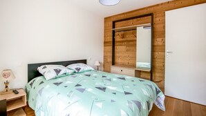 Un dormitorio con cama, mesita de noche, lámpara, espejo y armario.