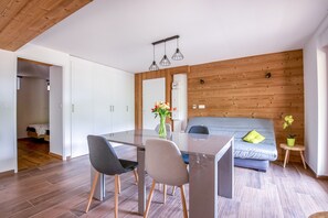 Un espacio habitable moderno con comedor, sofá y una pequeña mesita de noche con planta en maceta.